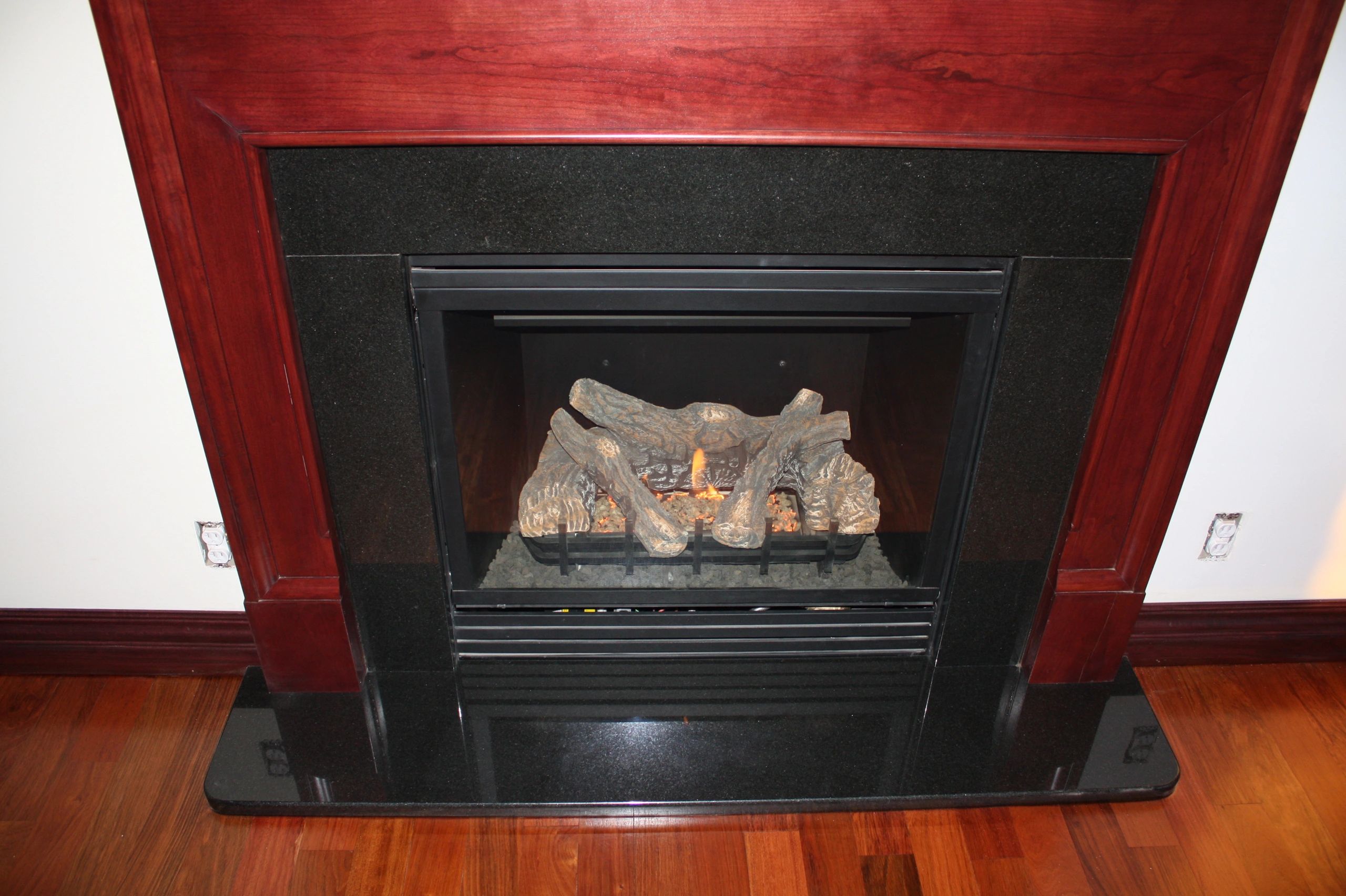Modern fireplace with red wood surround and black granite