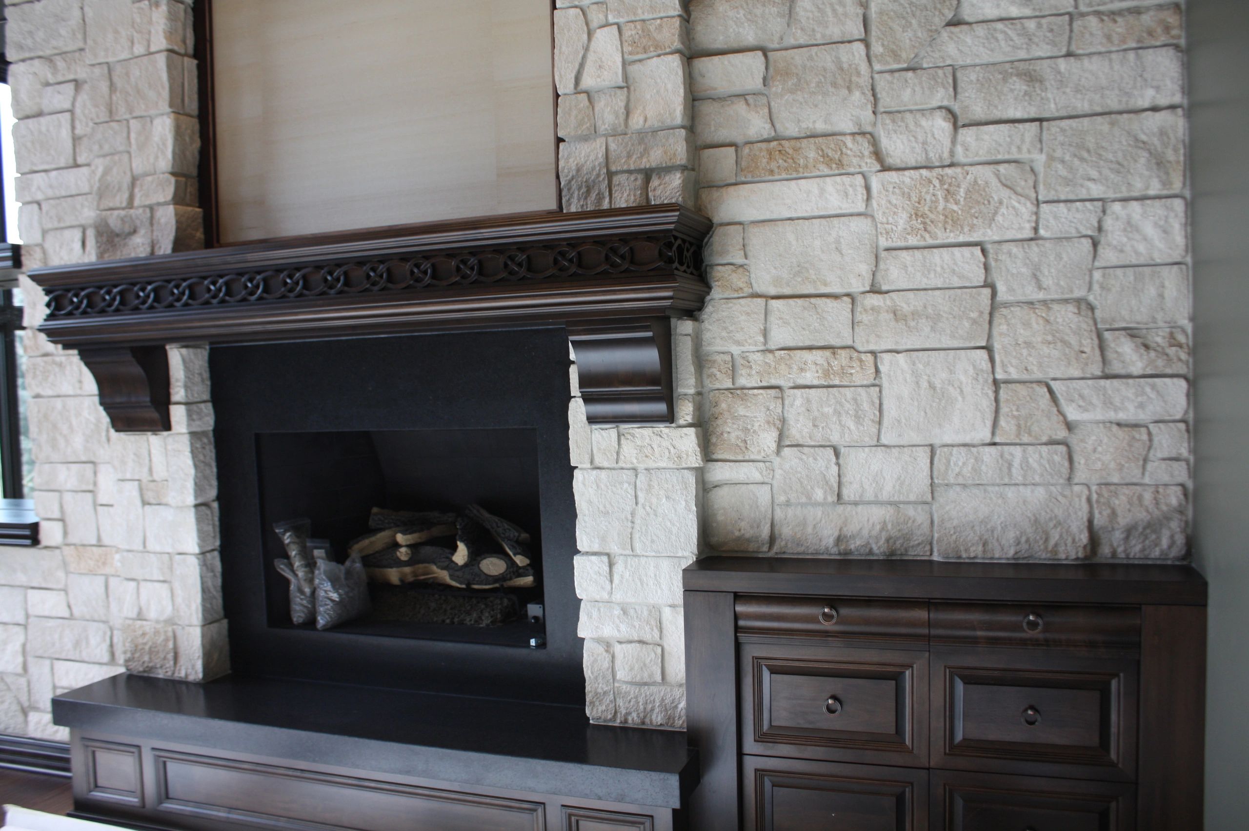 Luxurious fireplace with cream stone surround and dark wood cabinetry