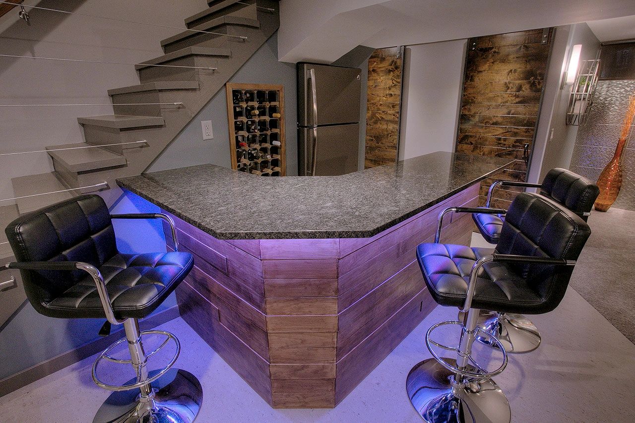 Modern basement bar with stone countertop and LED lighting