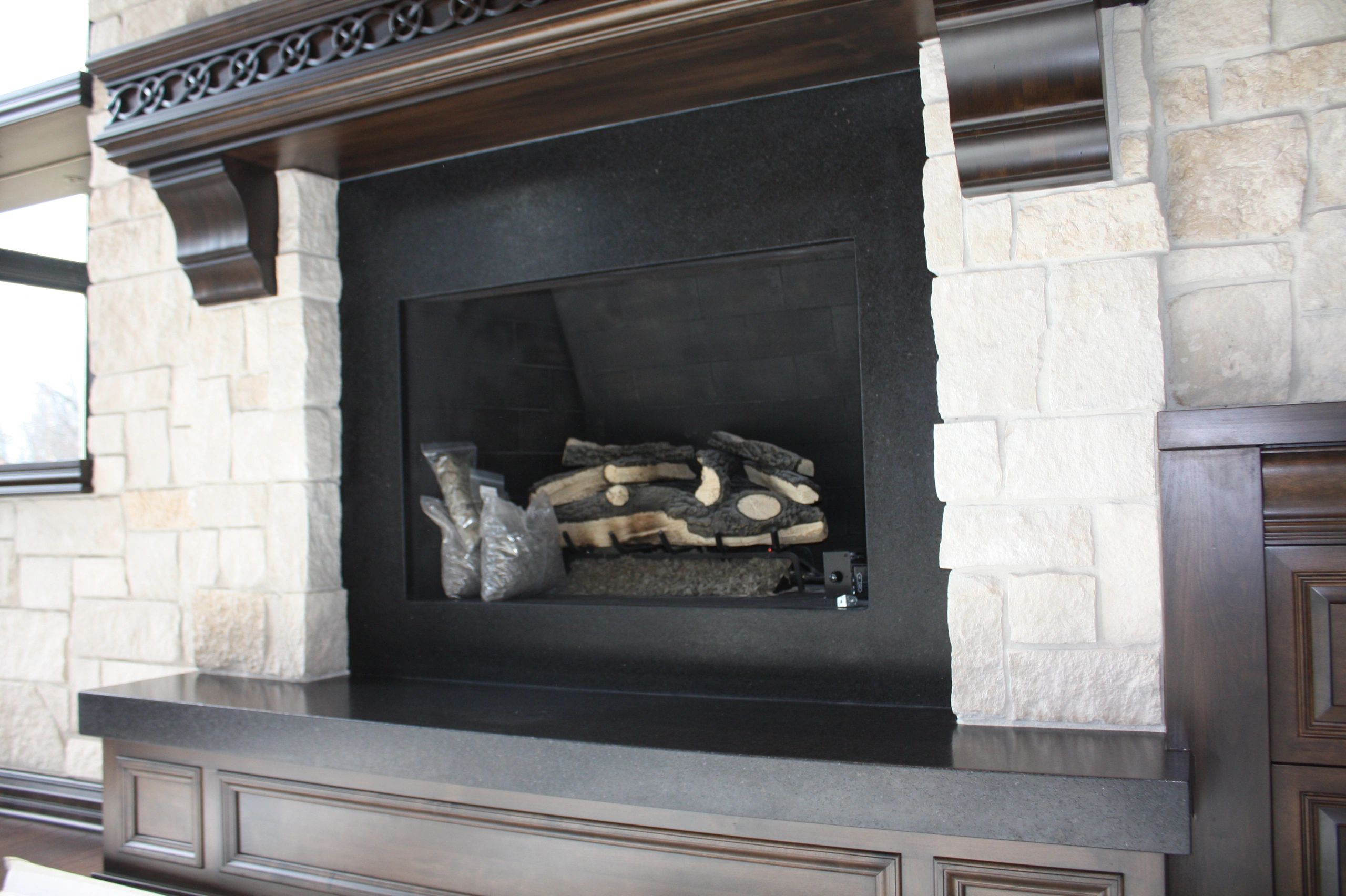 Cream stone fireplace with black gas insert — Dekton surface example